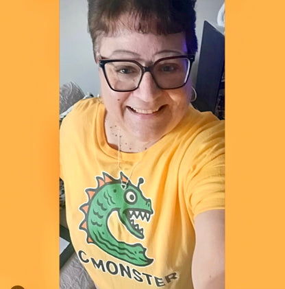 Person wearing a yellow t-shirt with a green monster graphic and the text 'C MONSTER'.
