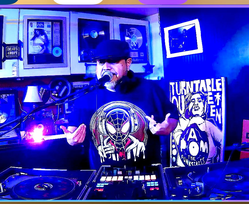 Person standing behind turntables in a music store with records and equipment in the background.