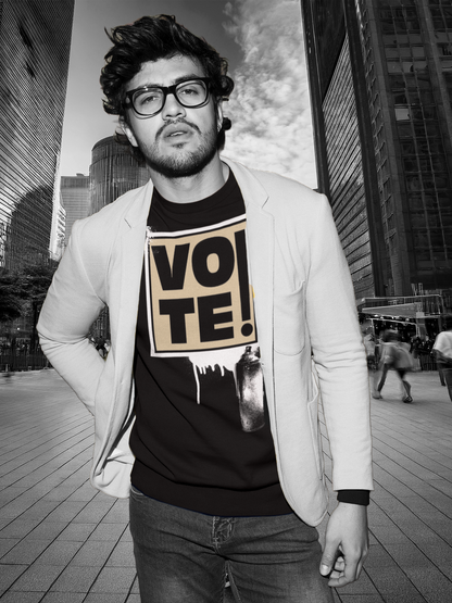 A man wearing a black graphic t-shirt with a beige 'VOTE!' print, styled with a light-colored blazer and dark jeans, set against a blurred black-and-white city street background.